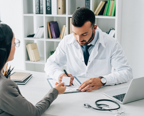Patient giving id card to general practitioner to fill insurance claim form in clinic