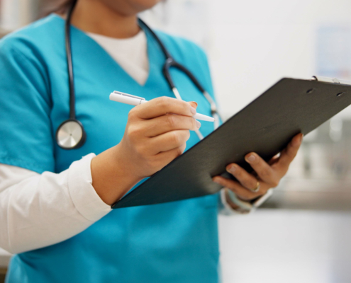 Side view of a nurse writing something on clipboard