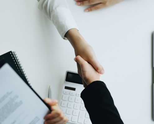 Insurance agent shaking hand with client, top-down view
