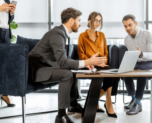 business people looking over insurance plans on laptop