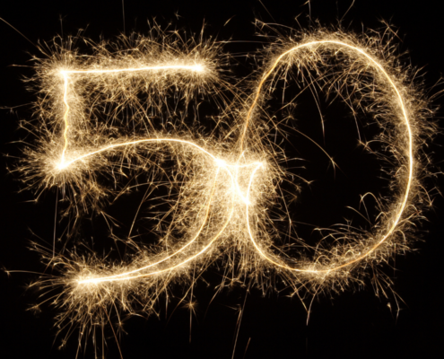 The number 50 written in glowing golden sparklers against a solid black background, celebrating a fiftieth anniversary or birthday.